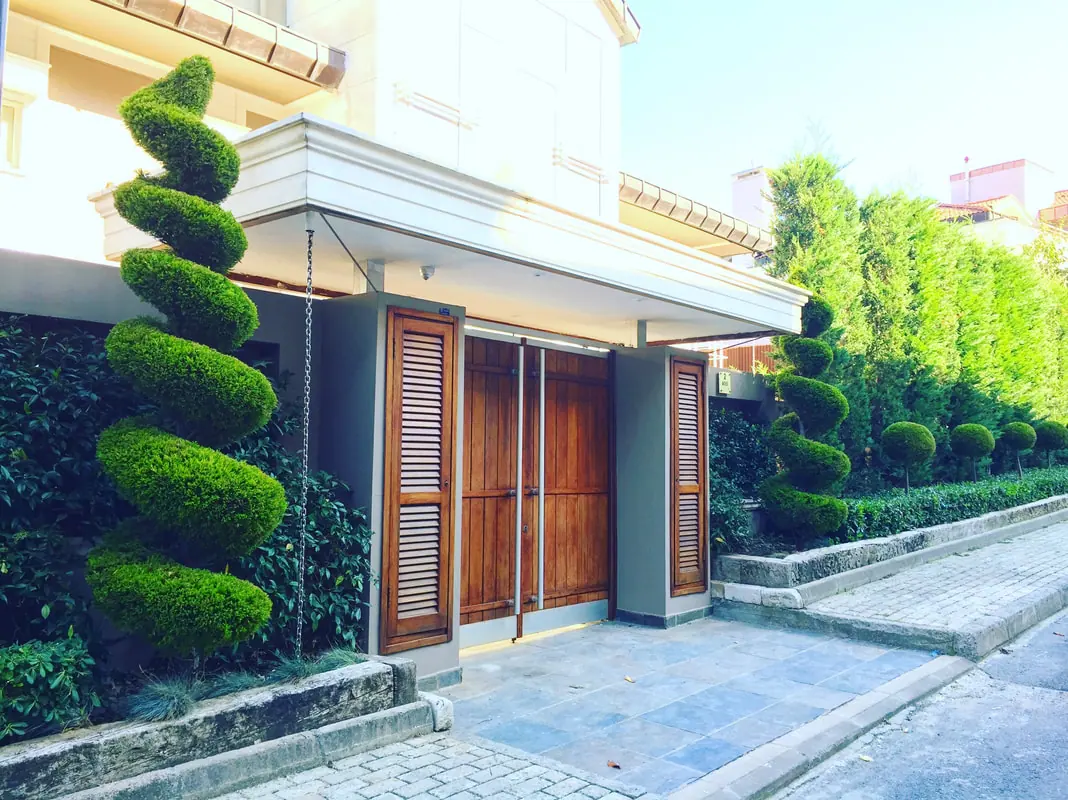 Halat Holding A-85 no’lu villa girişinde spiral formlu bitkiler ve çit duvarı