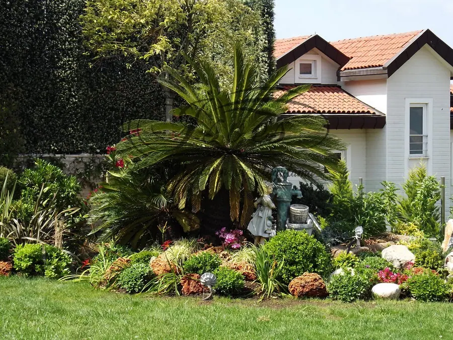 Palmiye, sikas ve renkli çiçek tarhlarıyla düzenlenen villa bahçesi